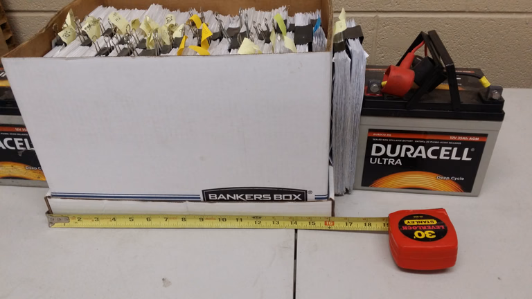 The failed and returned record stack, about 17.5 inches, next to a battery for scale